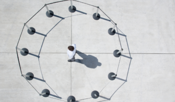 Person alone inside a ring of barrier posts showing capability constrained by organizational design, Clarion Consulting