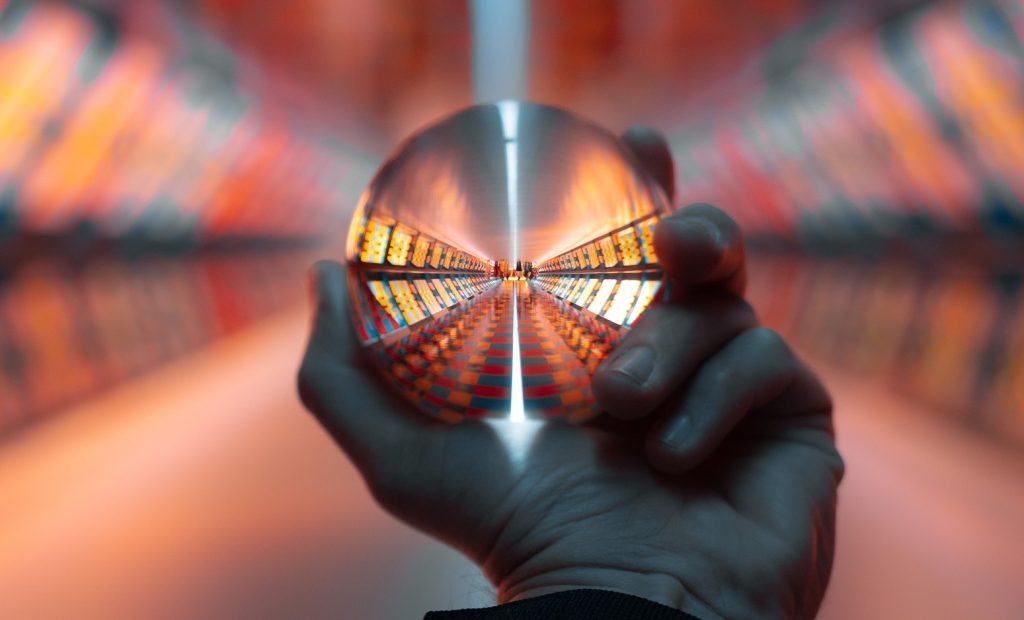 A closeup of a hand holding a lens ball in a pedestrian tunnel, a vertical shot